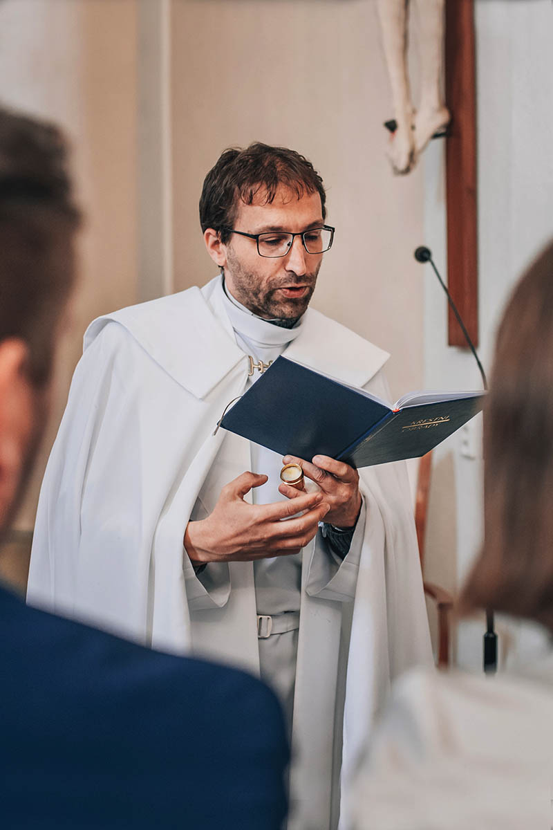 Pan farář čte motlitbu při křestu.