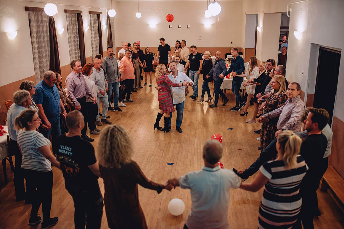 Oslavenkyně na oslavě padesátin tančí se svým manželem v kroužku rodiny a přátel.